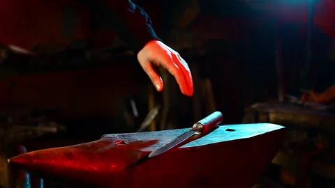 Blacksmith, A man blacksmith forging a hot knife blade using a hammer Stock Footage 150736112