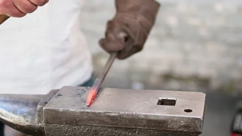 Blacksmith manually forging the heated metal Stock Footage 258620039