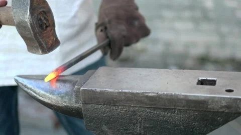 Blacksmith manually forging the heated metal Stock Footage 258620323