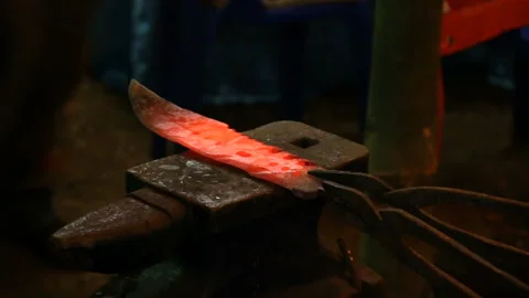Blacksmith manually forging hot metal knife on anvil in traditional Stock Footage 154975659