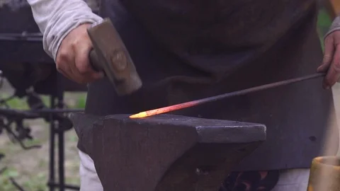 Blacksmith manually forging metal rod in outdoor smithy during Slavic and Stock Footage 113557167