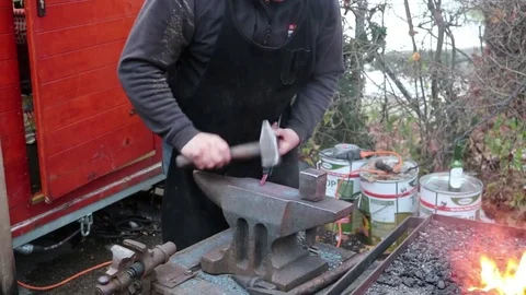 The blacksmith manually forging the molten metal on the anvil in smithy with Stock Footage 83475864