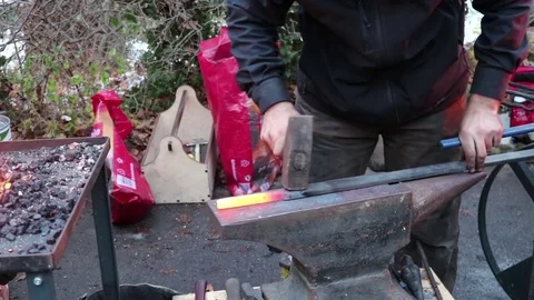 The blacksmith manually forging the molten metal on the anvil in smithy with Видео 83475871