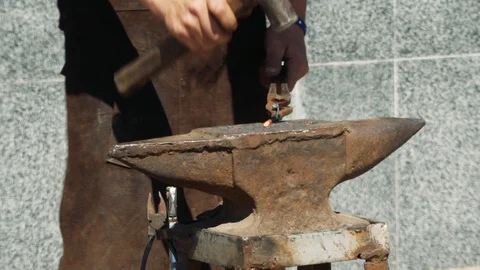 Blacksmith manually forging the molten metal on the anvil in smithy with spar Stock-Footage 110836397