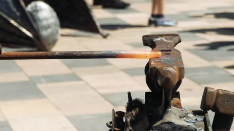 The blacksmith manually forging the molten metal on the anvil in smithy with  Stockbeeldmateriaal 110836489