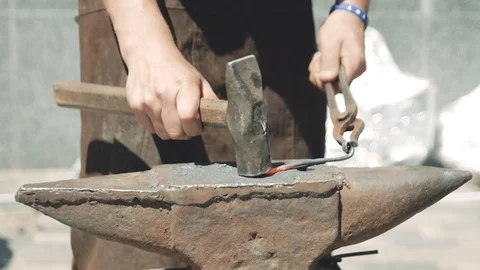 Blacksmith manually forging the molten metal on the anvil in smithy with spar Stock Footage 111265396