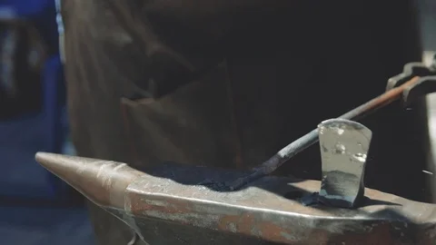 The blacksmith manually forging the molten metal on the anvil in smithy with  Vidéo 111265587