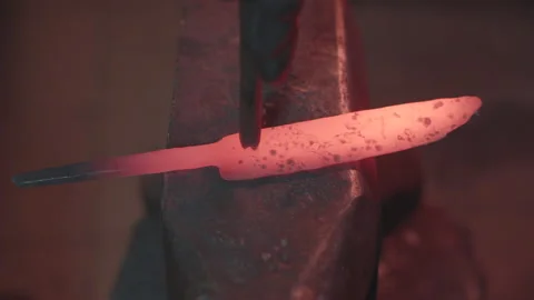 Blacksmith manually forging molten metal in smithy workshop. Damascus steel k Stock Footage 194486440