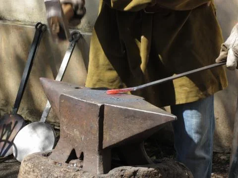Blacksmith manually forging the molten metal with hammer on the anvil Stock Photos