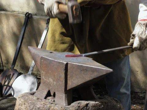 Blacksmith manually forging the molten metal with hammer on the anvil Stock Photos
