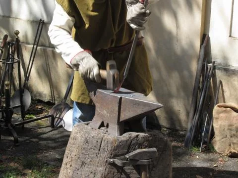 Blacksmith manually forging the molten metal with hammer on the anvil Stock Photos