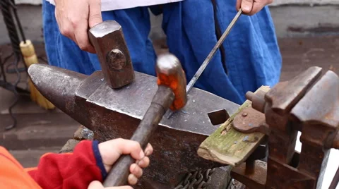 A blacksmith models a bar of iron with hammer after took it from fire forge. Stock Footage 62111582
