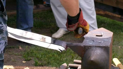 A blacksmith models a bar of iron with hammer after took it from fire forge. Stock Footage 66236762