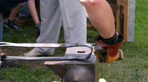 A blacksmith models a bar of iron with hammer after took it from fire forge. Stock Footage 66236984