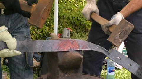 A blacksmith models a bar of iron with hammer after took it from fire forge. Stock Footage 66237091