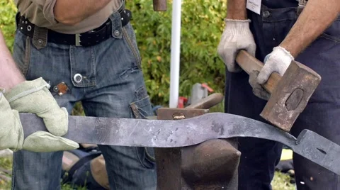 A blacksmith models a bar of iron with hammer after took it from fire forge. Stock Footage 66237236