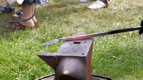 A blacksmith models a bar of iron with hammer after took it from fire forge. Stock Footage 66237510