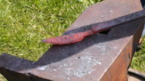 A blacksmith models a bar of iron with hammer after took it from fire forge. Stock Footage 66238616