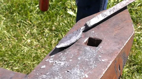A blacksmith models a bar of iron with hammer after took it from fire forge. Stock Footage 66238737