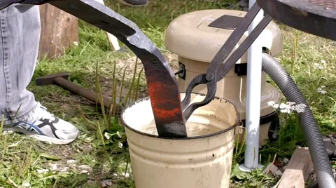 A blacksmith models a bar of iron with hammer after took it from fire forge. Stock Footage 66238841