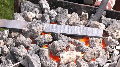 A blacksmith models a bar of iron with hammer after took it from fire forge. Stock Footage 66239036
