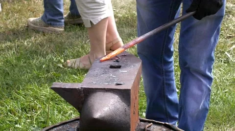 A blacksmith models a bar of iron with hammer after took it from fire forge. Stock Footage 66239368