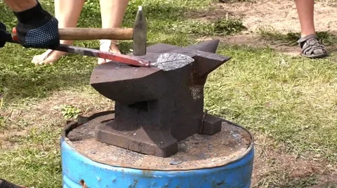 A blacksmith models a bar of iron with hammer after took it from fire forge. Stock Footage 66239840