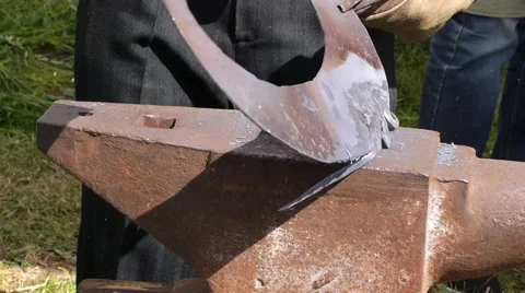 A blacksmith models a bar of iron with hammer after took it from fire forge. Stock Footage 66239897