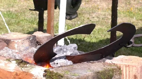 A blacksmith models a bar of iron with hammer after took it from fire forge. Stock Footage 66239970