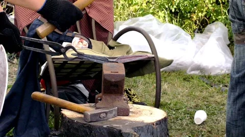 A blacksmith models a bar of iron with hammer after took it from fire forge. Stock Footage 66240053