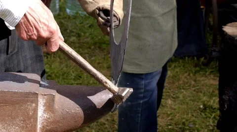 A blacksmith models a bar of iron with hammer after took it from fire forge. Stock Footage 66240102
