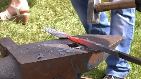 A blacksmith models a bar of iron with hammer after took it from fire forge. Stock Footage 66240156