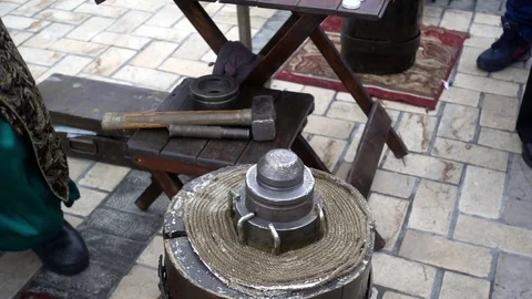 The blacksmith in old clothes strikes with a large hammer in slow motion Stock Footage 84032644