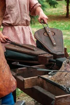Blacksmith with pair of bellows lighting fire in furnace Stock Photos