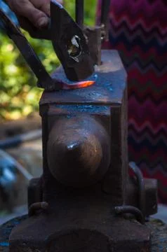 Blacksmith performs the forging of hot glowing metal on the anvil Stock Photos
