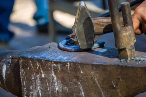 Blacksmith performs the forging of hot glowing horseshoe on the anvil Stock Photos