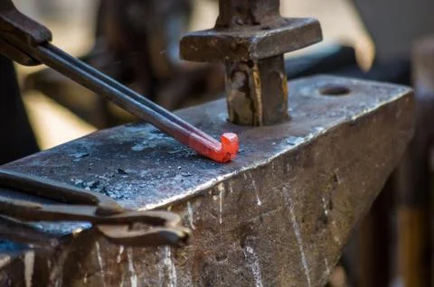 Blacksmith performs the forging of hot glowing horseshoe on the anvil Stock Photos