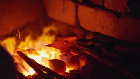 Blacksmith placing arrowhead into forge Stock Footage 245263154