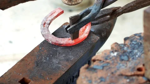 A blacksmith pounding a hammer on red-hot horseshoe on the anvil. Stock Footage 94267296