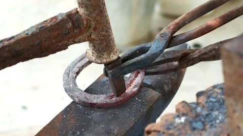 A blacksmith pounding a hammer on red-hot horseshoe on the anvil. Video stock 94267495