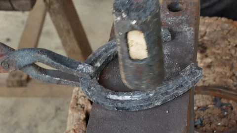 A blacksmith pounding a hammer on red-hot horseshoe on the anvil. Stock Footage 94267953