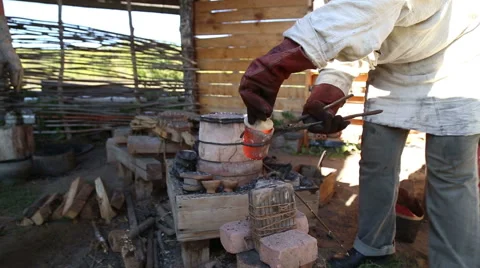 Blacksmith pours the molten metal from the heated crucible into the form for Stock Footage 54688588