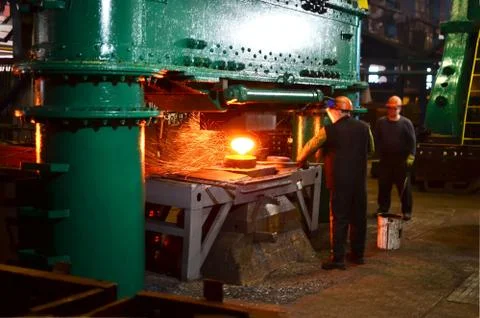 Blacksmith processes the red hot iron under a huge press. Foto stock