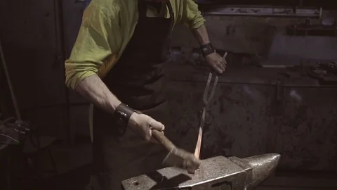The blacksmith processes the workpiece with a hammer on the anvil Stock Footage 108956460