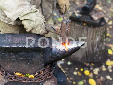 Blacksmith processing red hot iron rod on anvil Stock Photos