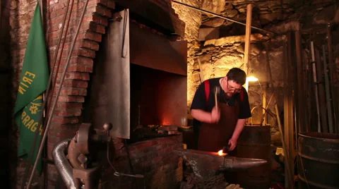 Blacksmith pulls hot iron from fire, forges in historic shop, slider, wide shot Stock Footage 39022366