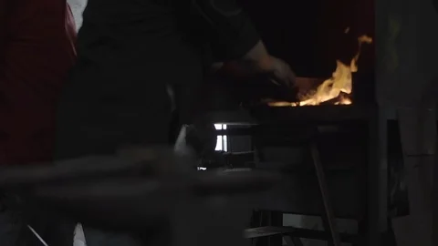 A blacksmith puts a hot glowing metal bar on the anvil, slow motion Video stock 122074070