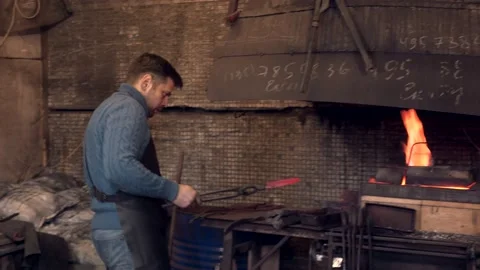 Blacksmith putting a hot iron twirl in burning fire Stock Footage 132653253