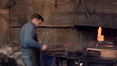 Blacksmith putting a hot iron twirl in burning fire Stock Footage 146747201