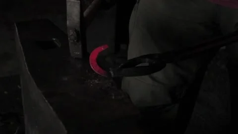A blacksmith, a red-hot horseshoe, a red horseshoe, hits an anvil with a hammer Video stock 163679079